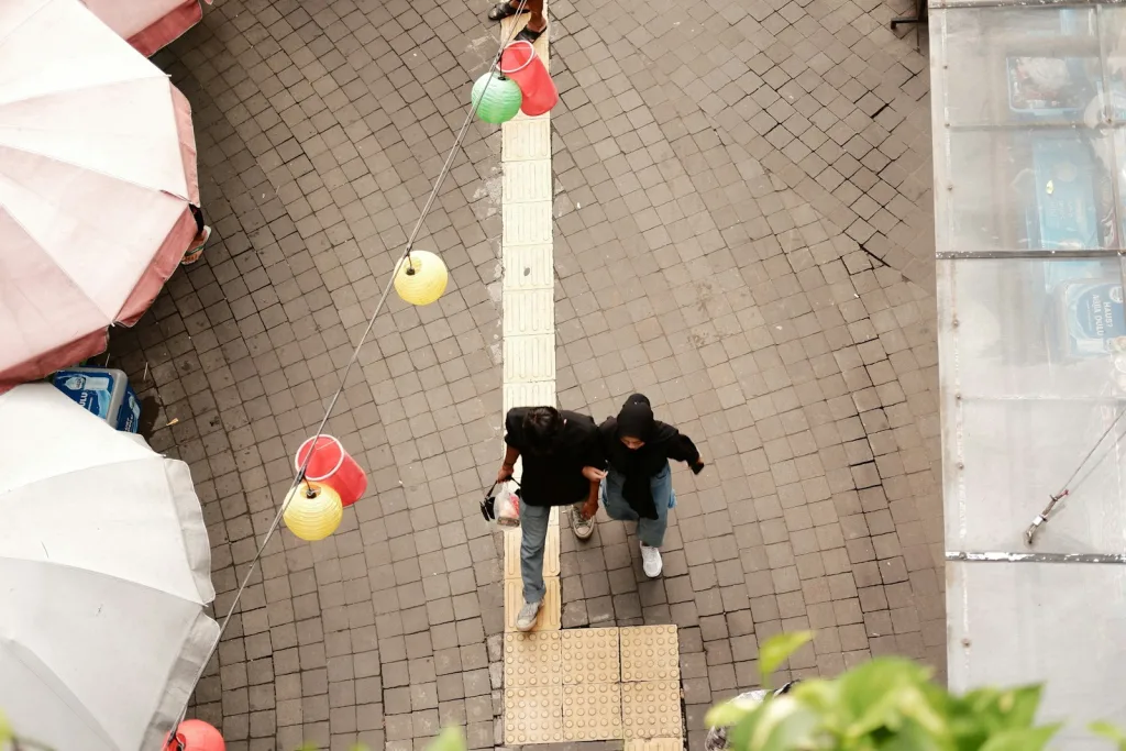 a couple of people walking down a street next to umbrellas