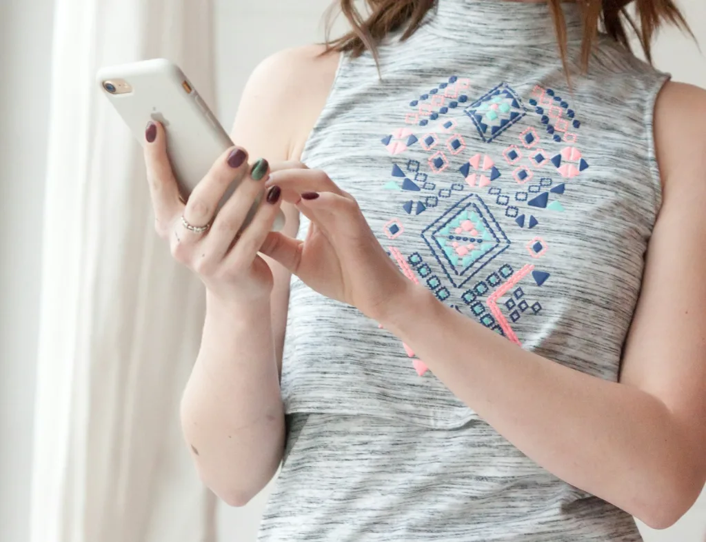 woman in teal and white tank top holding silver iphone 6