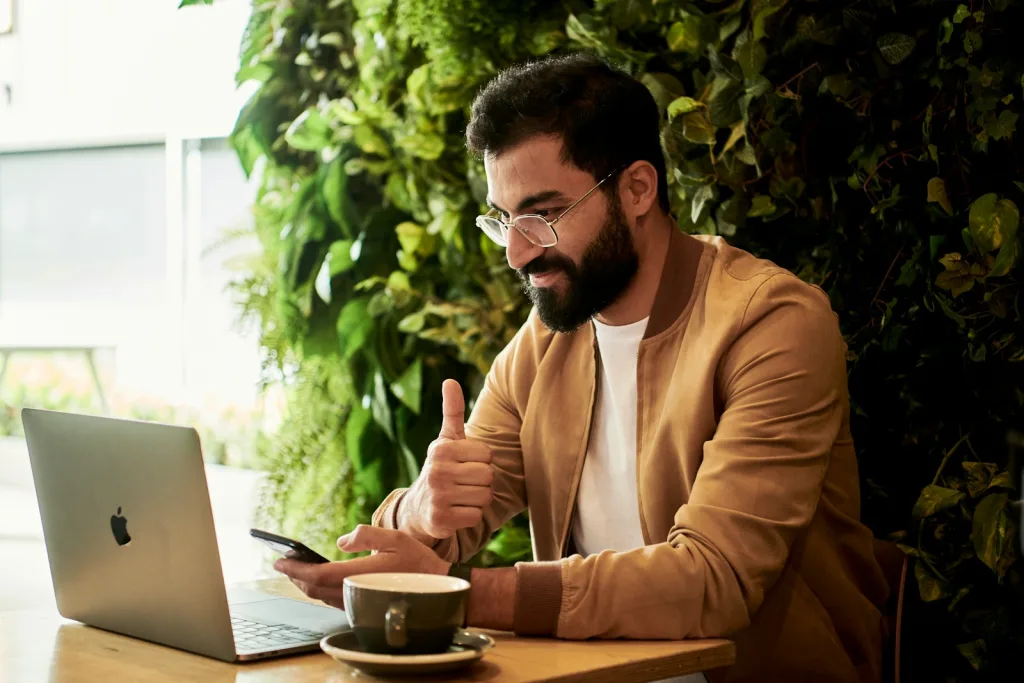 man in brown jacket sitting at a table looking at laptop